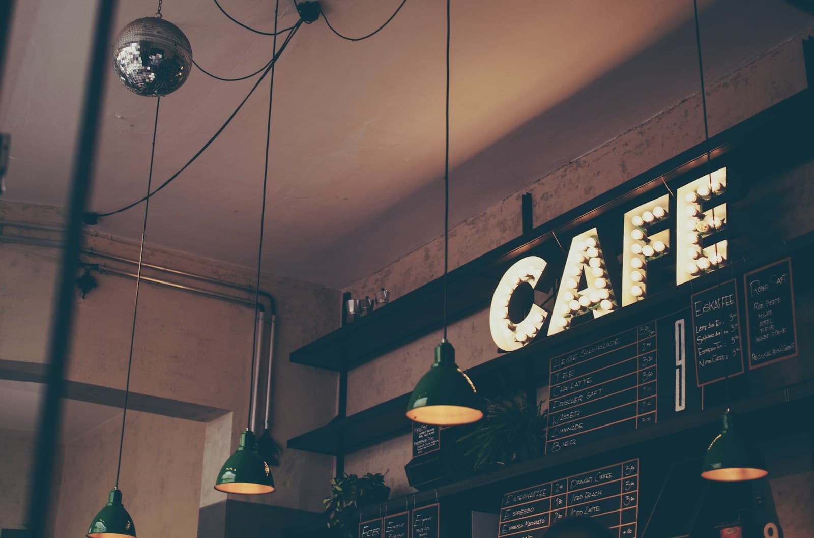 A cafe interior with pendant lights and an illuminated cafe sign